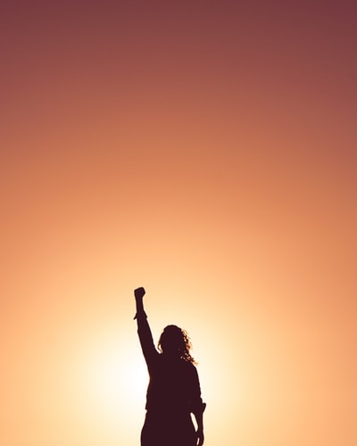Woman silhouette standing with fist in the air.